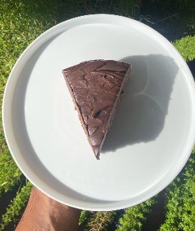 A wedge of dark chocolate tart with a smooth top, on a white plate.